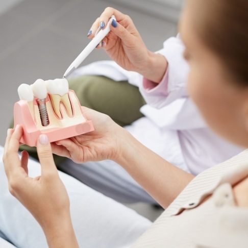 Dentist pointing to model smile with dental implant supported replacement tooth