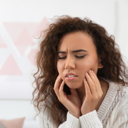 Woman holding jaw in pain before emergency dentistry