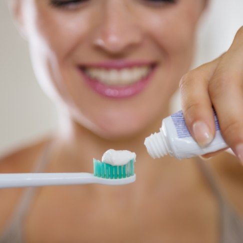 Woman putting toothpaste on toothbrush