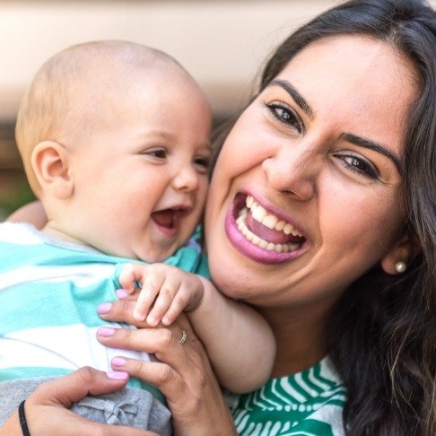 Mother holding laughing baby after frenectomy for lip and tongue tie