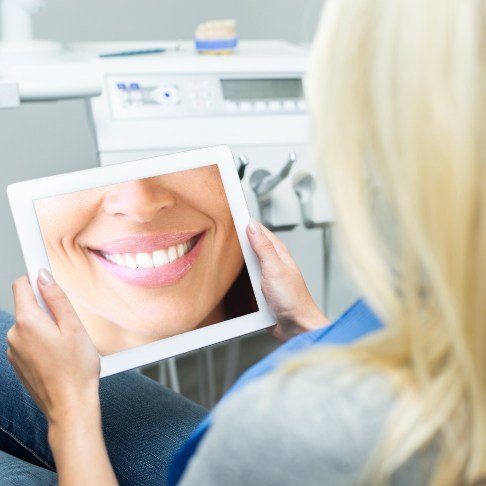 Woman looking at virtual smile design on tablet computer screen