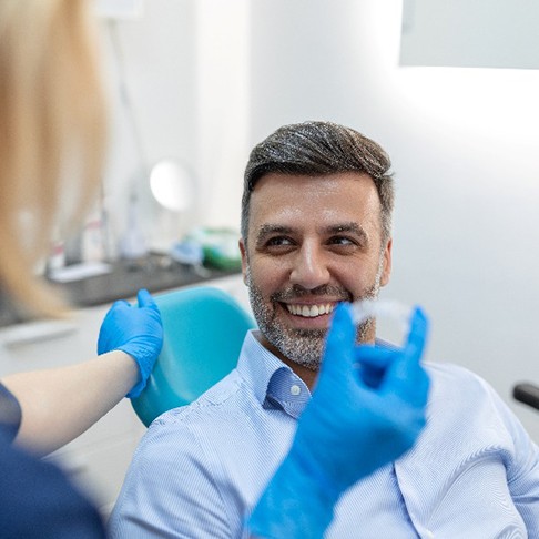 Man smiling at dentist who is holding Invisalign aligner