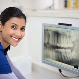 Dental assistant smiling while looking at patient's X-ray