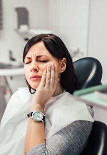 a patient holding her cheek due to tooth pain near Highland Park