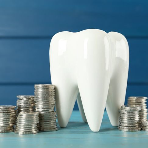 A large ceramic tooth next to silver coins