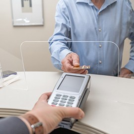 A man paying the cost of dental veneers