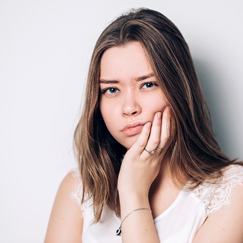 Woman holding cheek because of jaw pain