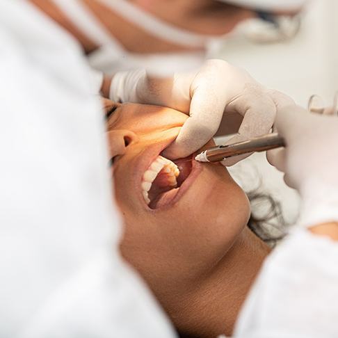 Dentist with white gloves numbing patient's mouth