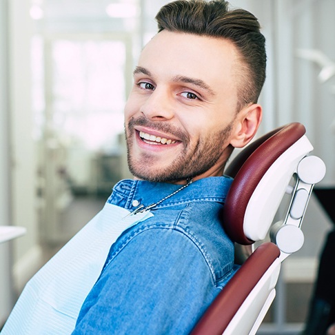Man in denim shirt smiling while sitting in treatment chair